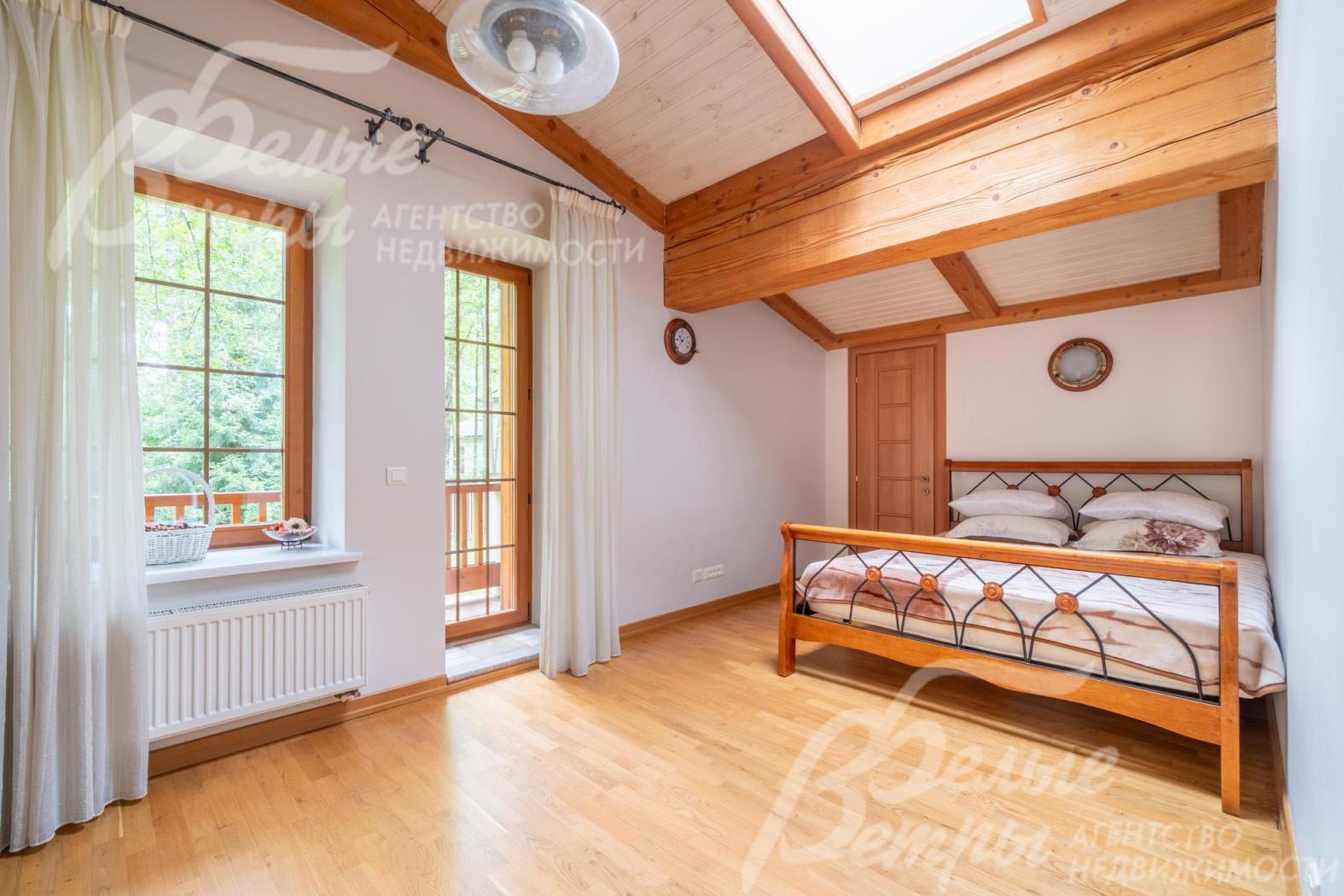 Уютная спальня на втором этаже с выходом на балкон, тёплую атмосферу в ней создаёт натуральная деревянная отделка