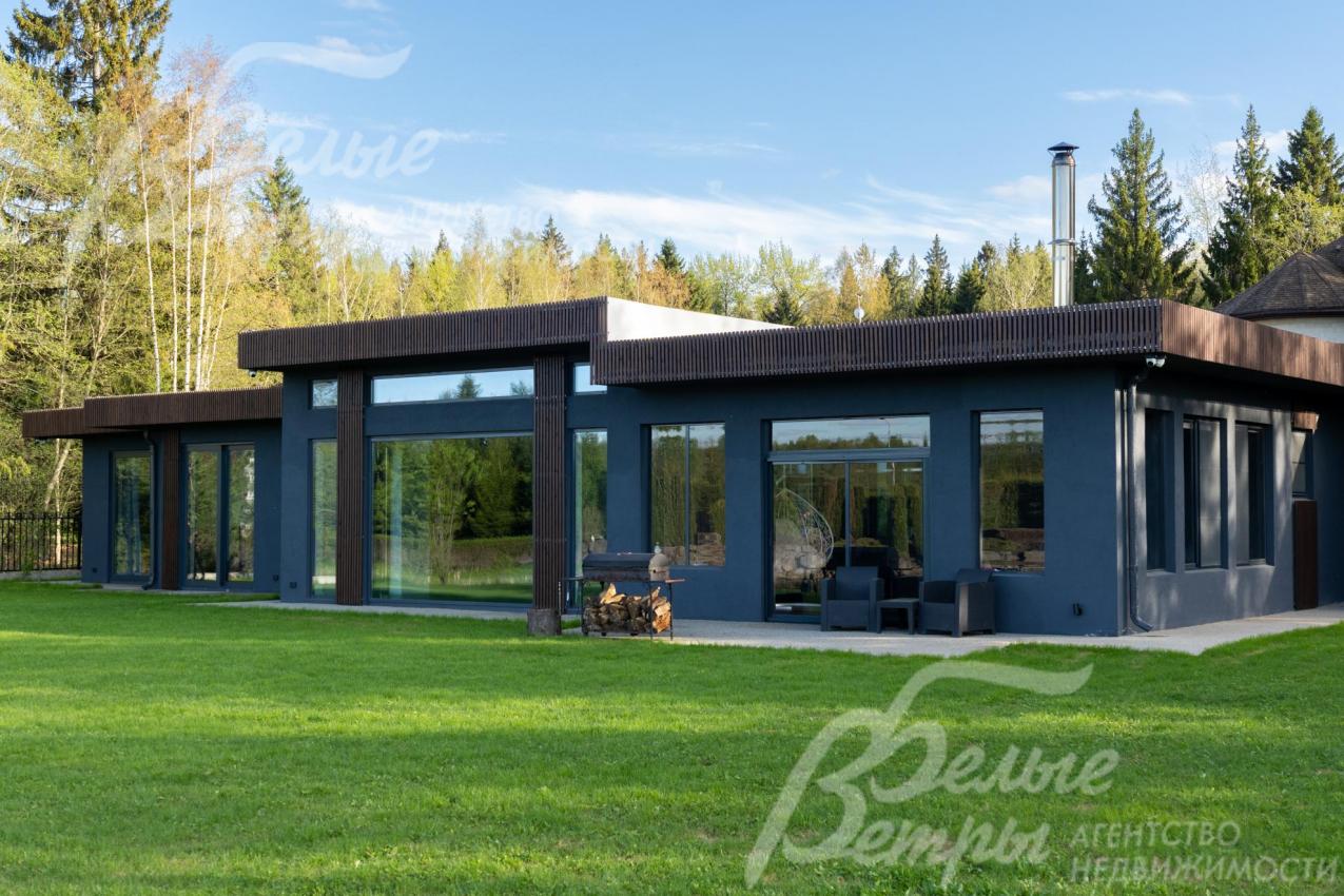 Дом - одноэтажный, с панорамным остеклением, в стиле минимализма. C деревьями и ландшафтом, в окружении леса.