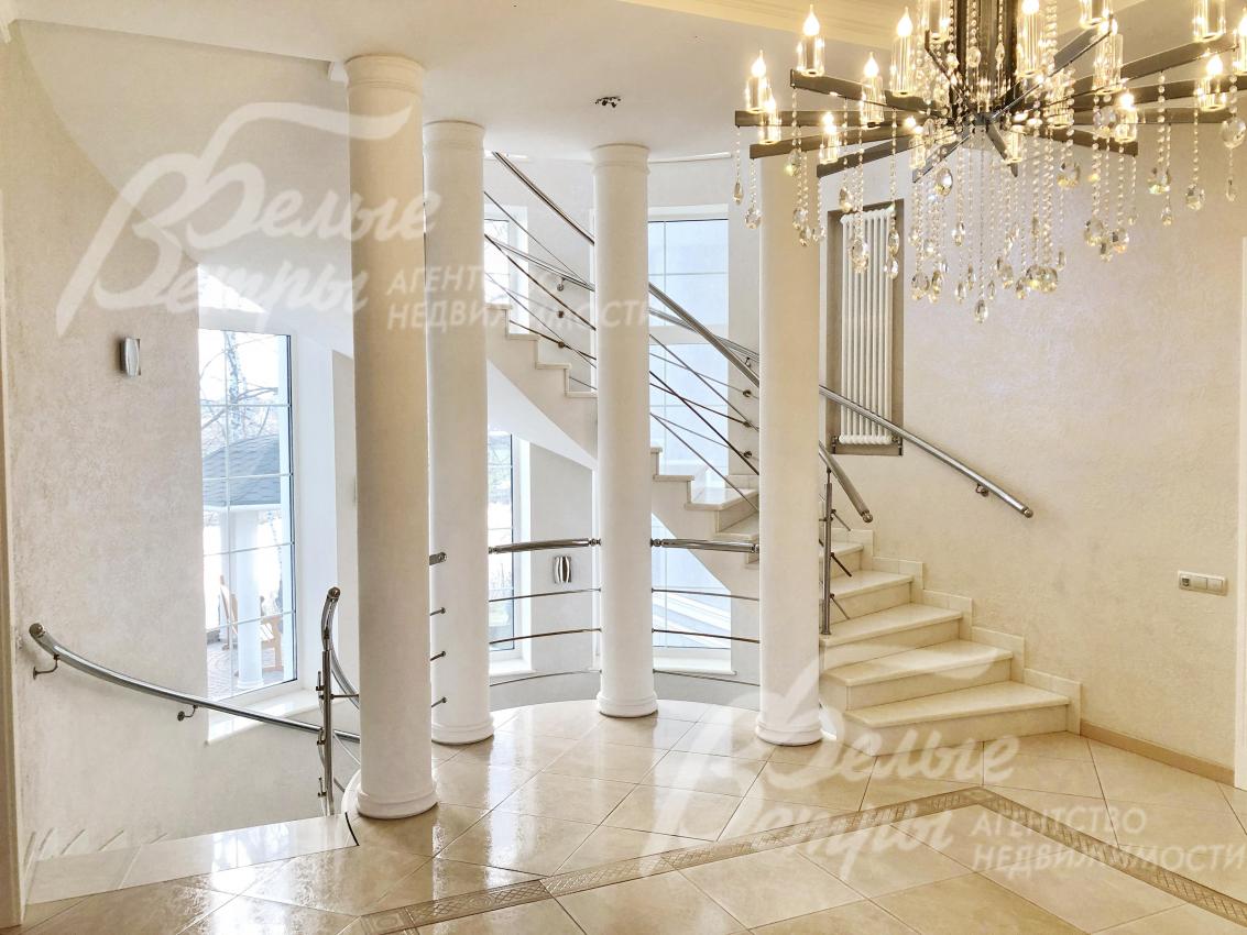 Внутри дома - красивая широкая круговая лестница, обрамленная колоннами и отделанная мрамором
