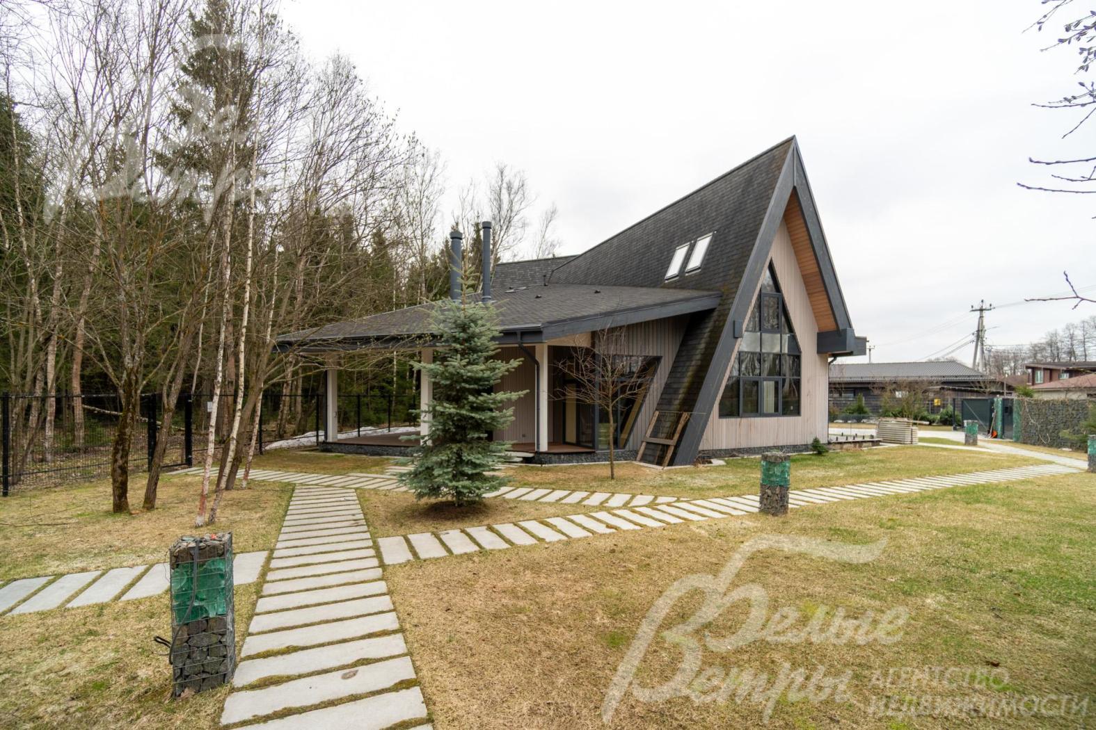 Дом стоит на участке с профессиональным ландшафтным дизайном: идеальные газоны сочетаются с плиточными дорожками чёткой геометрии