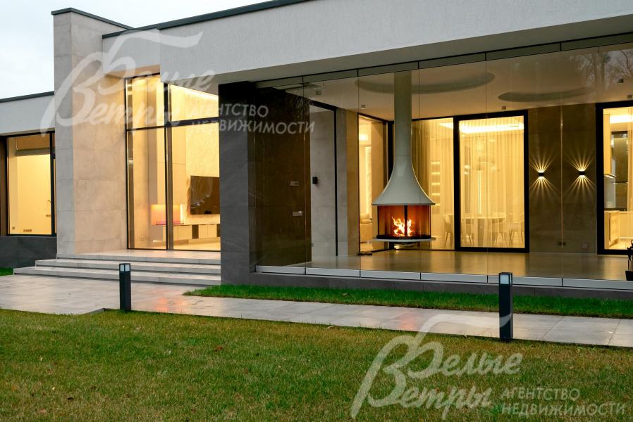 Вид с участка на крытую террасу-барбекю с подвесным дровяным камином