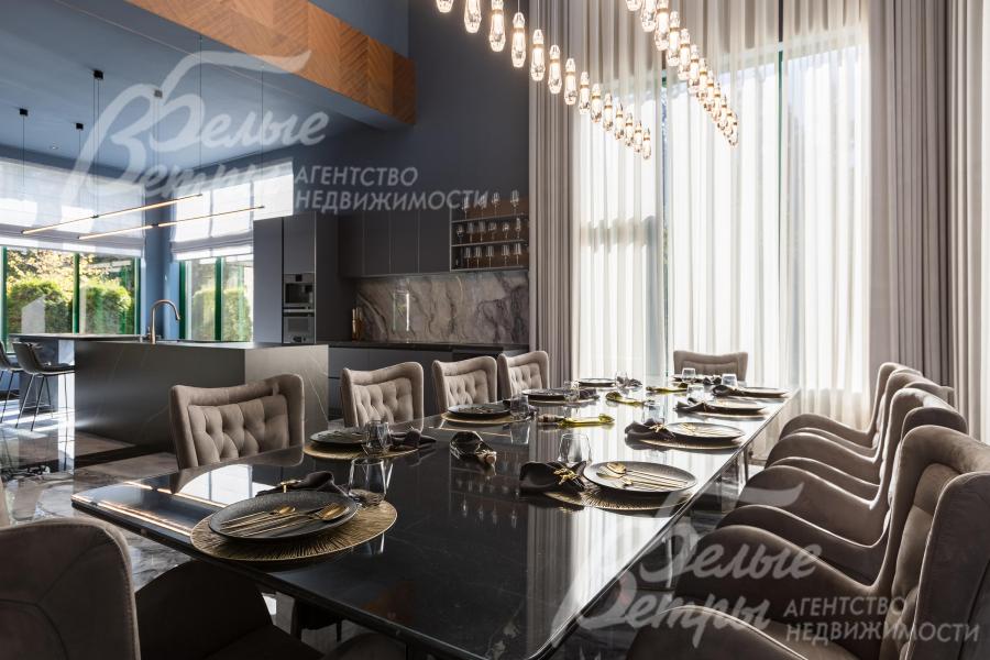 В зоне столовой размещён гарнитур на десять персон — стол со стеклянной поверхностью и креслами
