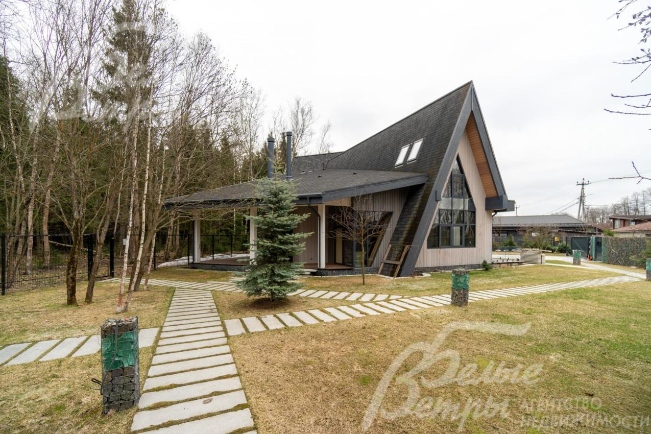 Дом стоит на участке с профессиональным ландшафтным дизайном: идеальные газоны сочетаются с плиточными дорожками чёткой геометрии