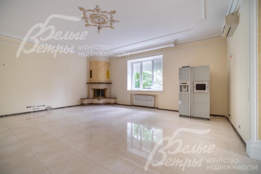 Просторную гостиную украшает угловой камин и декоративная роспись на потолке