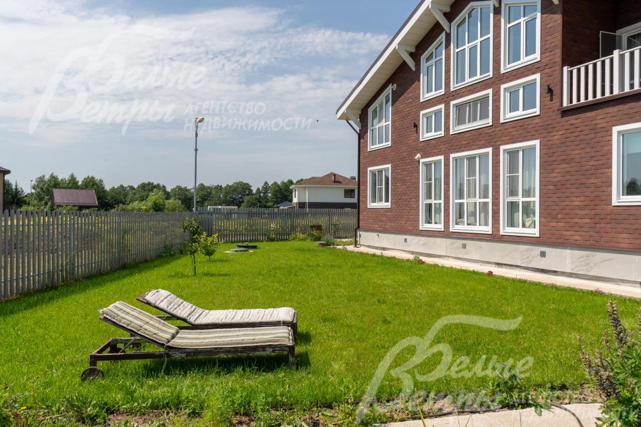 Дом стоит на благоустроенном участке с высаженным газоном, цветами и декоративными деревьями