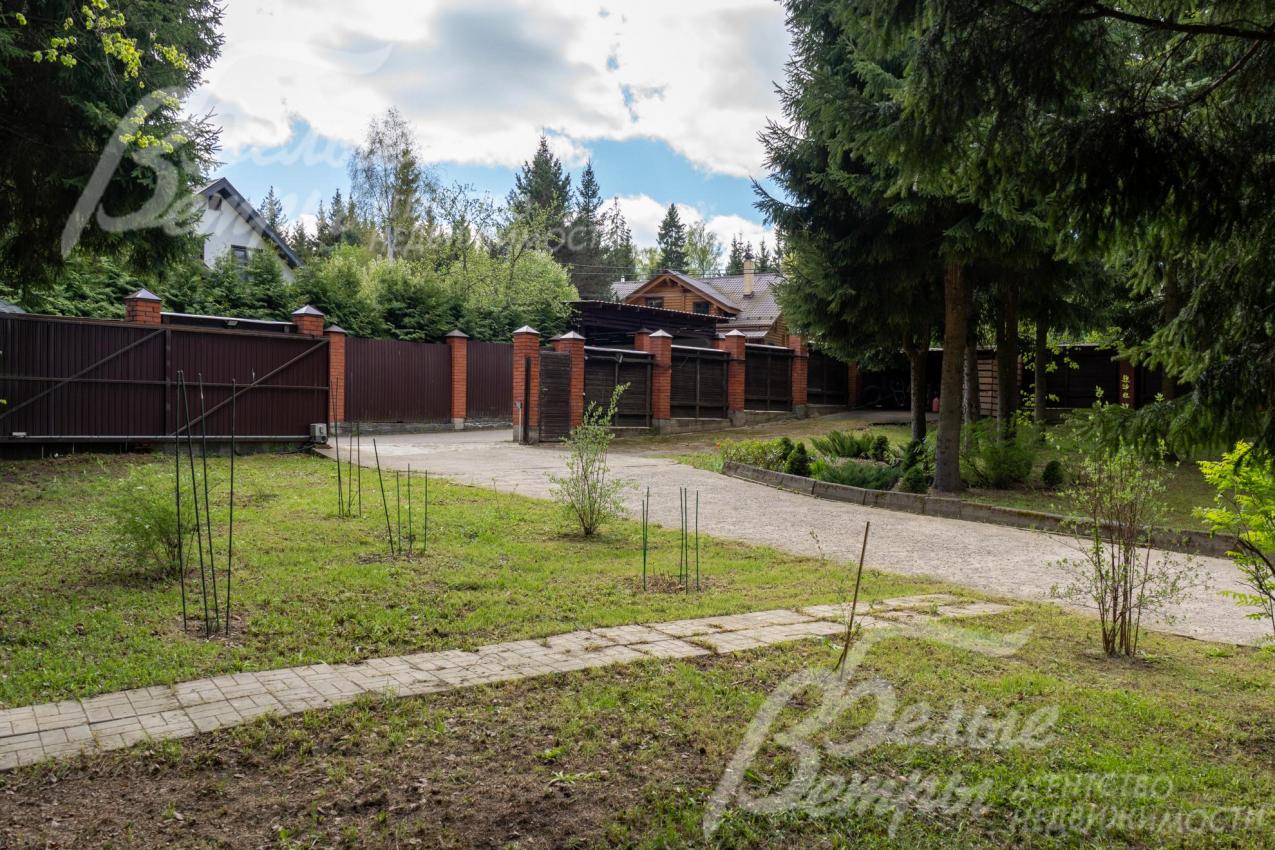 В верхней части участка – ровная возвышенность с высаженным газоном, декоративными деревьями и растениями, дорожками из натурального камня