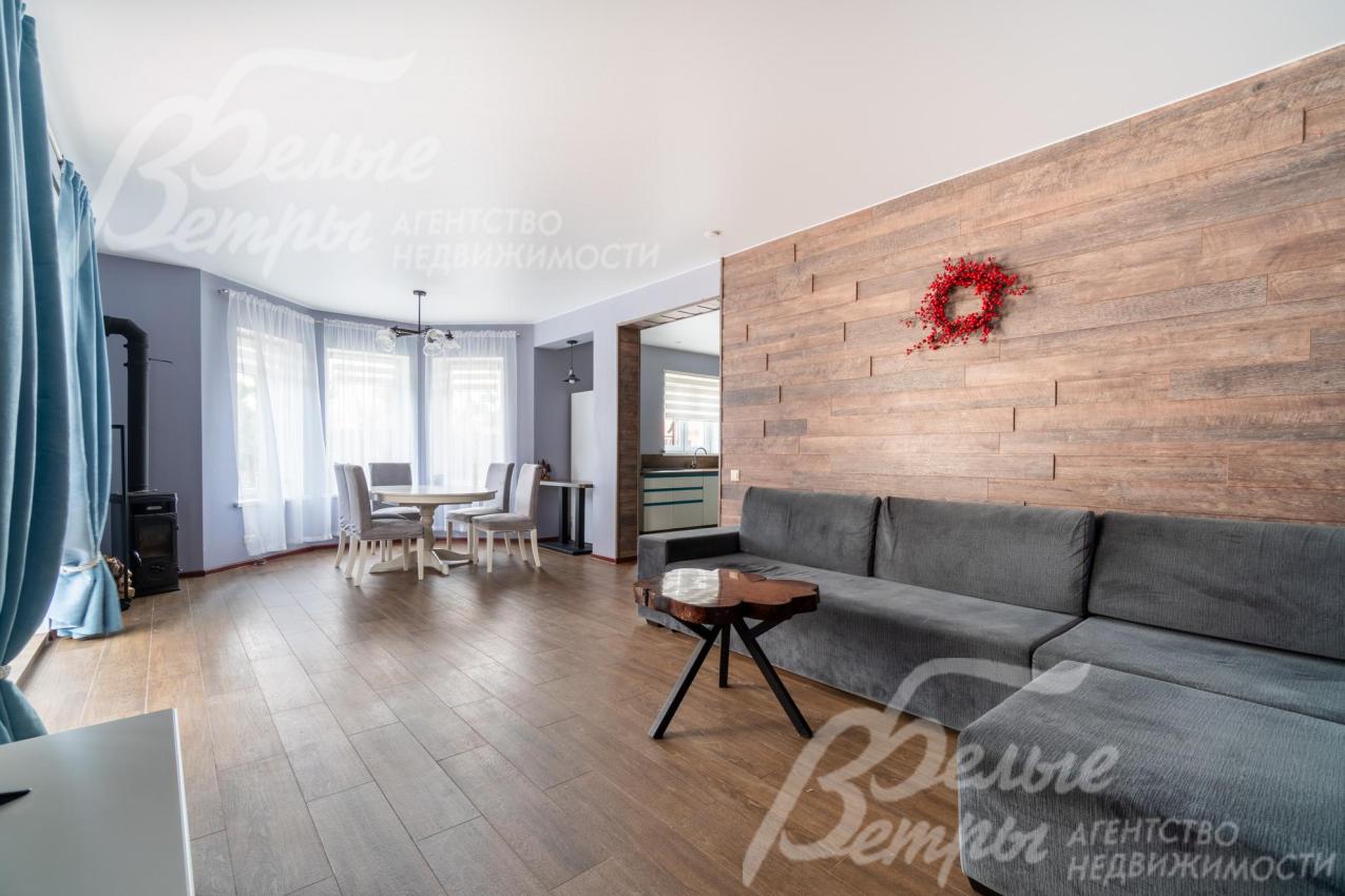 В доме выполнена стильная уютная отделка: в зоне гостиной - акцентная стена за диваном, оформленная панелями под дерево, которые гармонируют с оттенком напольного покрытия