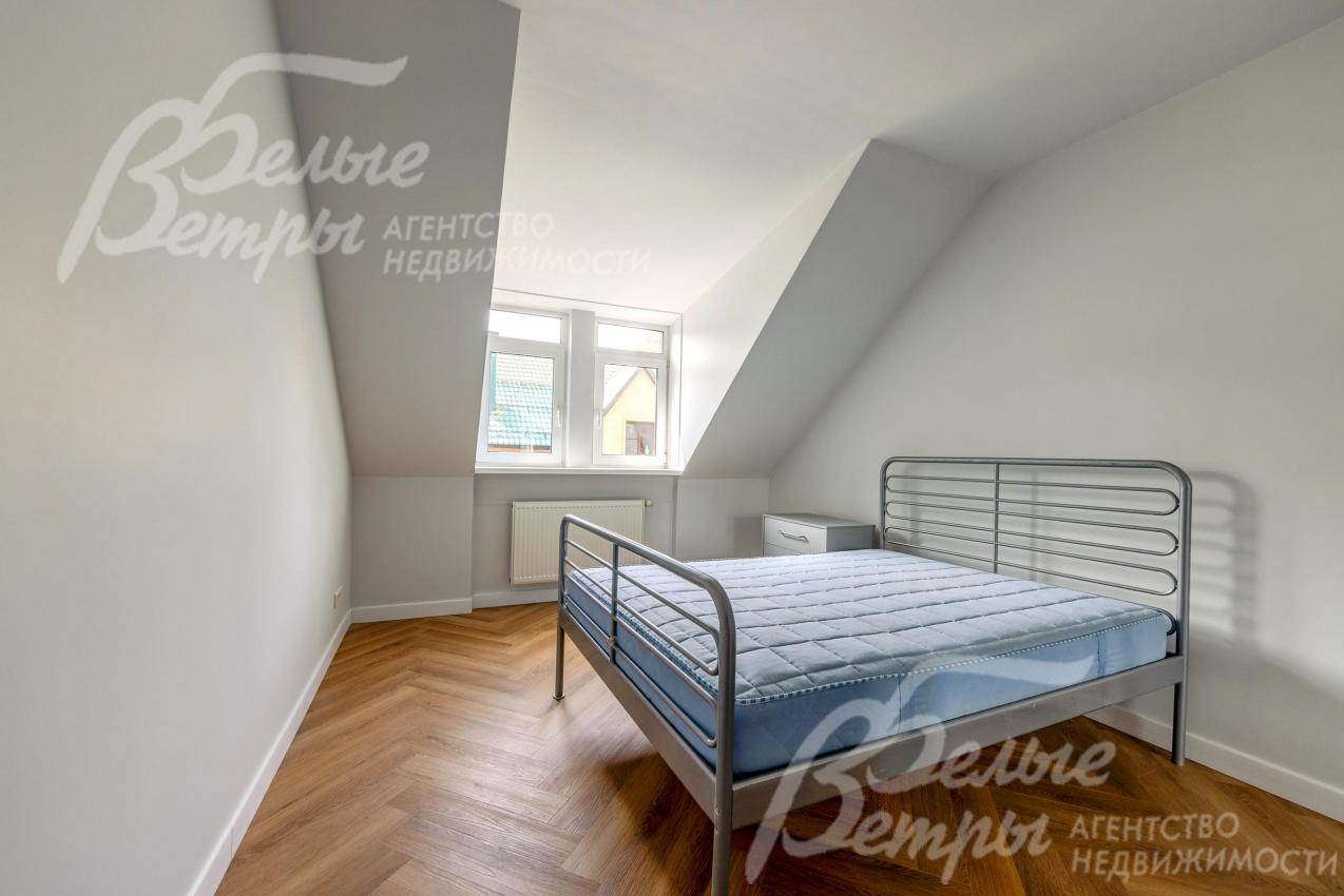 Одна из спален второго этажа со скошенными потолками, которые создают уютную атмосферу