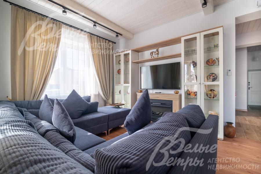 В гостиной основного дома - диванная группа, широкоформатный телевизор, электрический камин и шкафы-витрины