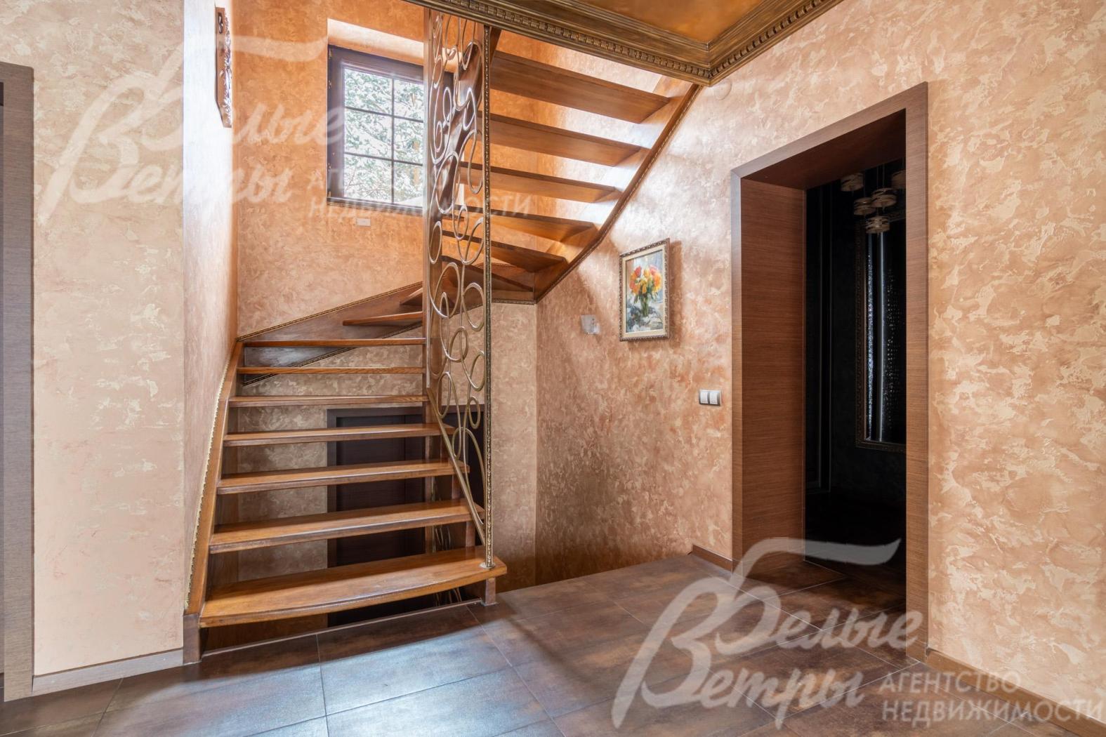 На второй этаж ведёт эффектная парящая лестница с каркасом и ступенями из массива дуба, коваными поручнями и перилами
