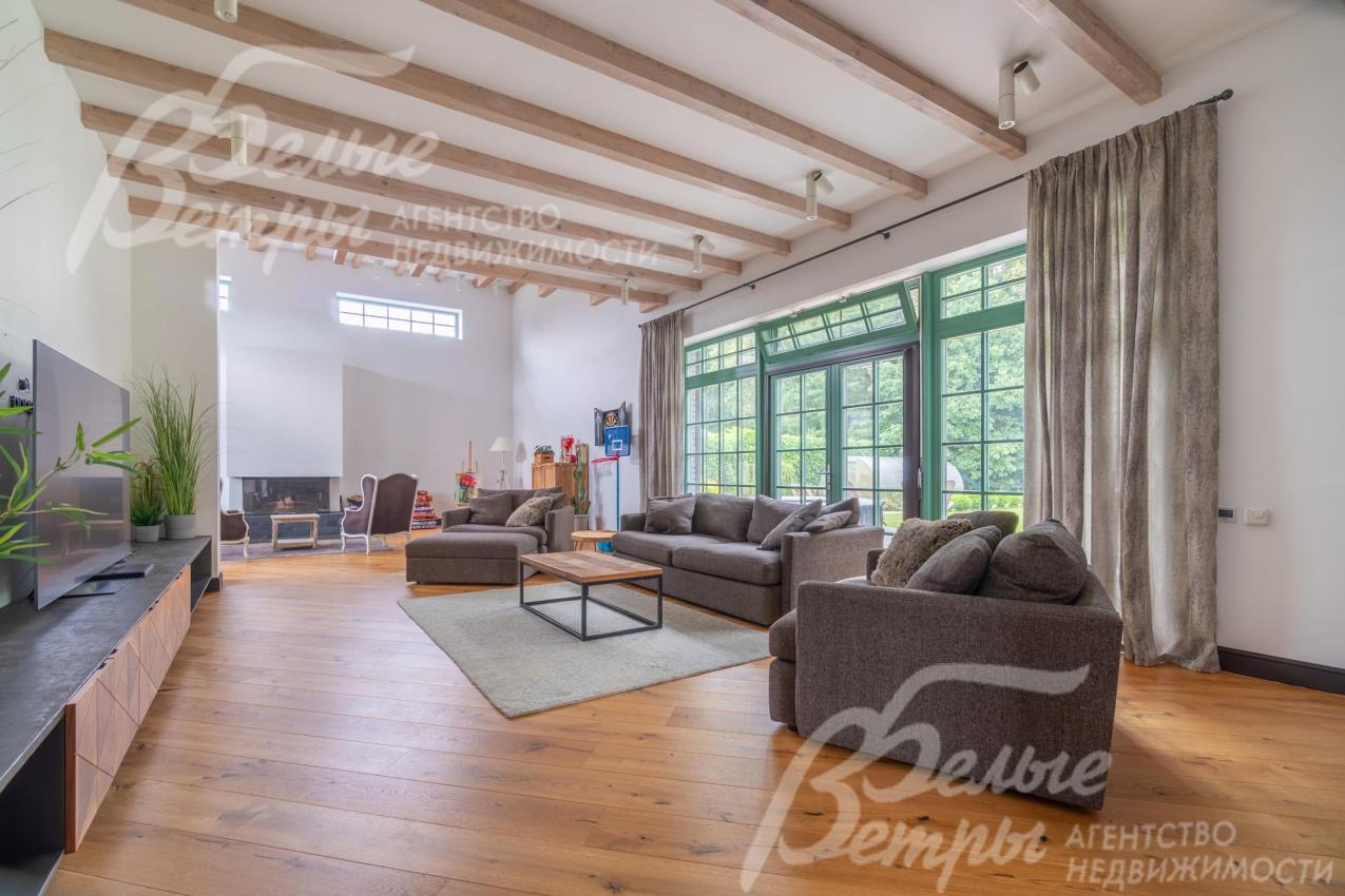 Гостиная с большой площадью остекления и высокими потолками. Окна - деревянные. Из гостиной - выход на террасу