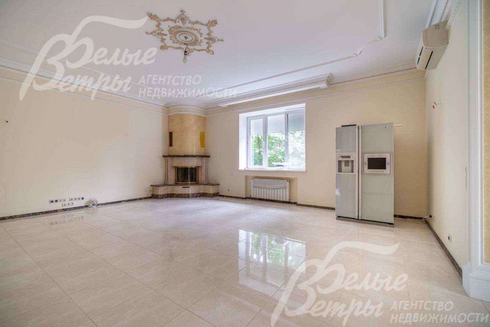 Просторную гостиную украшает угловой камин и декоративная роспись на потолке