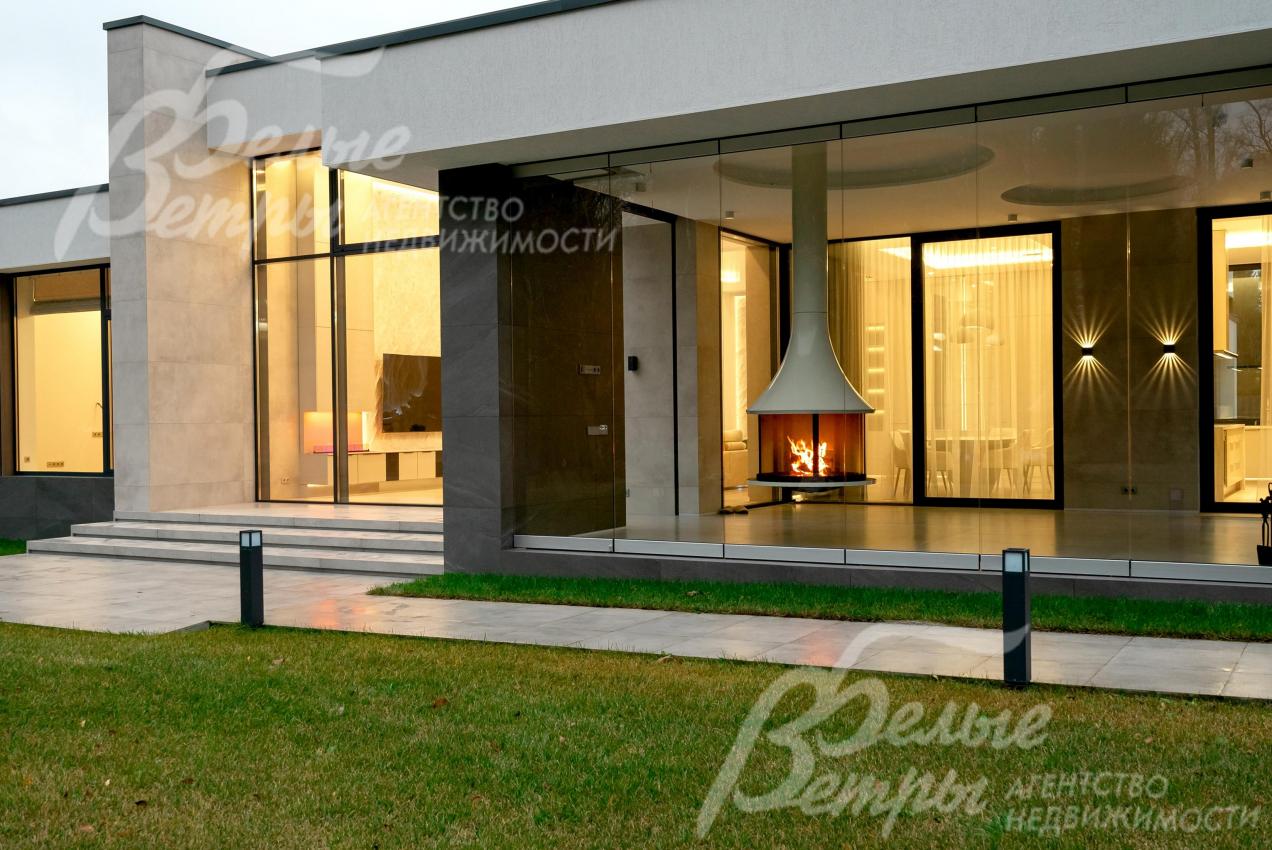 Вид с участка на крытую террасу-барбекю с подвесным дровяным камином