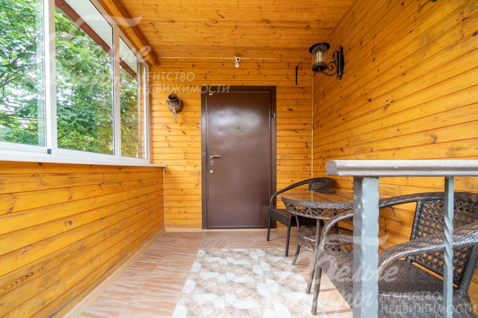 Уютное крытое застекленное крыльцо-терраса при входе в дом, с садовой мебелью