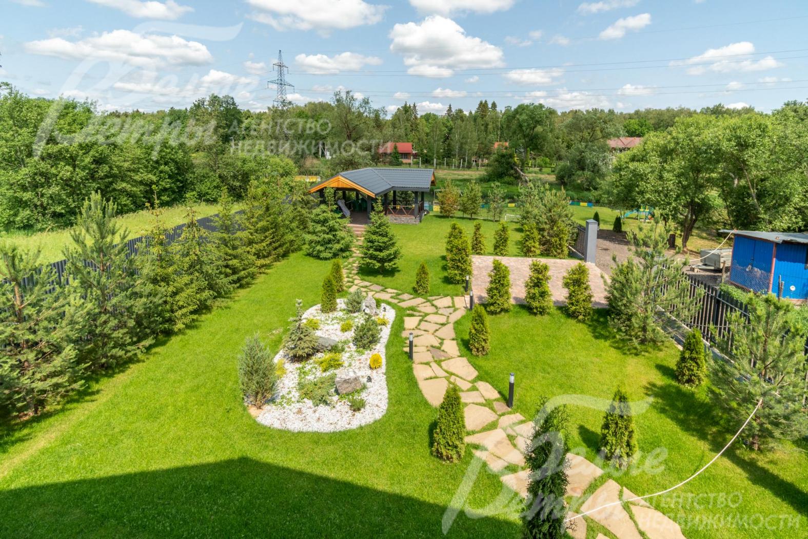 С балкона открывается панорамный вид на участок, окружающие его деревья и реку