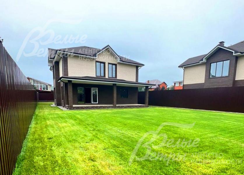 Дом стоит на ровном зелёном участке с газоном