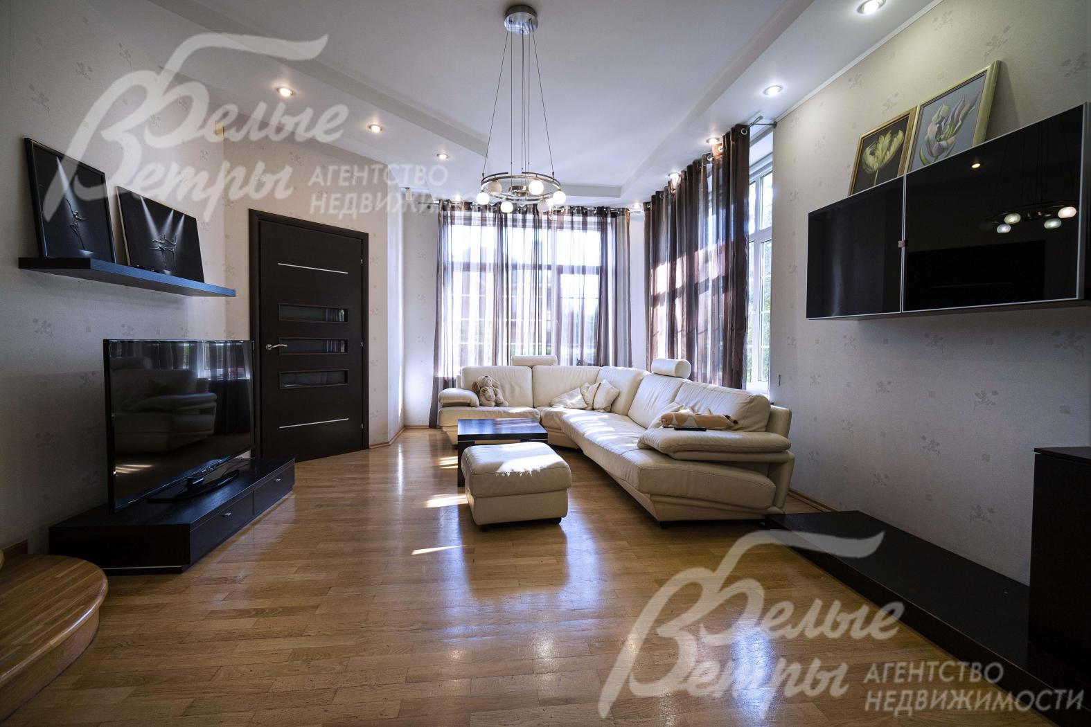 Гостиная на первом этаже дома с большой площадью остекления у диванной группы