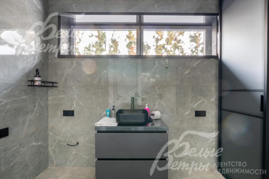 Чёрная прямоугольная раковина у окна гармонично сочетается с общим цветовым решением и подчёркивает сдержанную элегантность интерьера