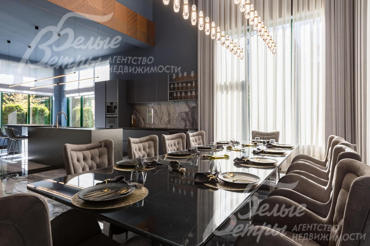 В зоне столовой размещён гарнитур на десять персон — стол со стеклянной поверхностью и креслами