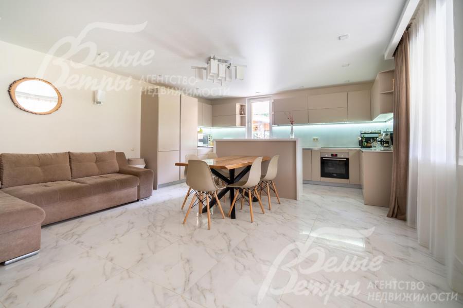 Просторная кухня-гостиная на первом этаже: установлен кухонный гарнитур с островом, обеденный стол из карагача