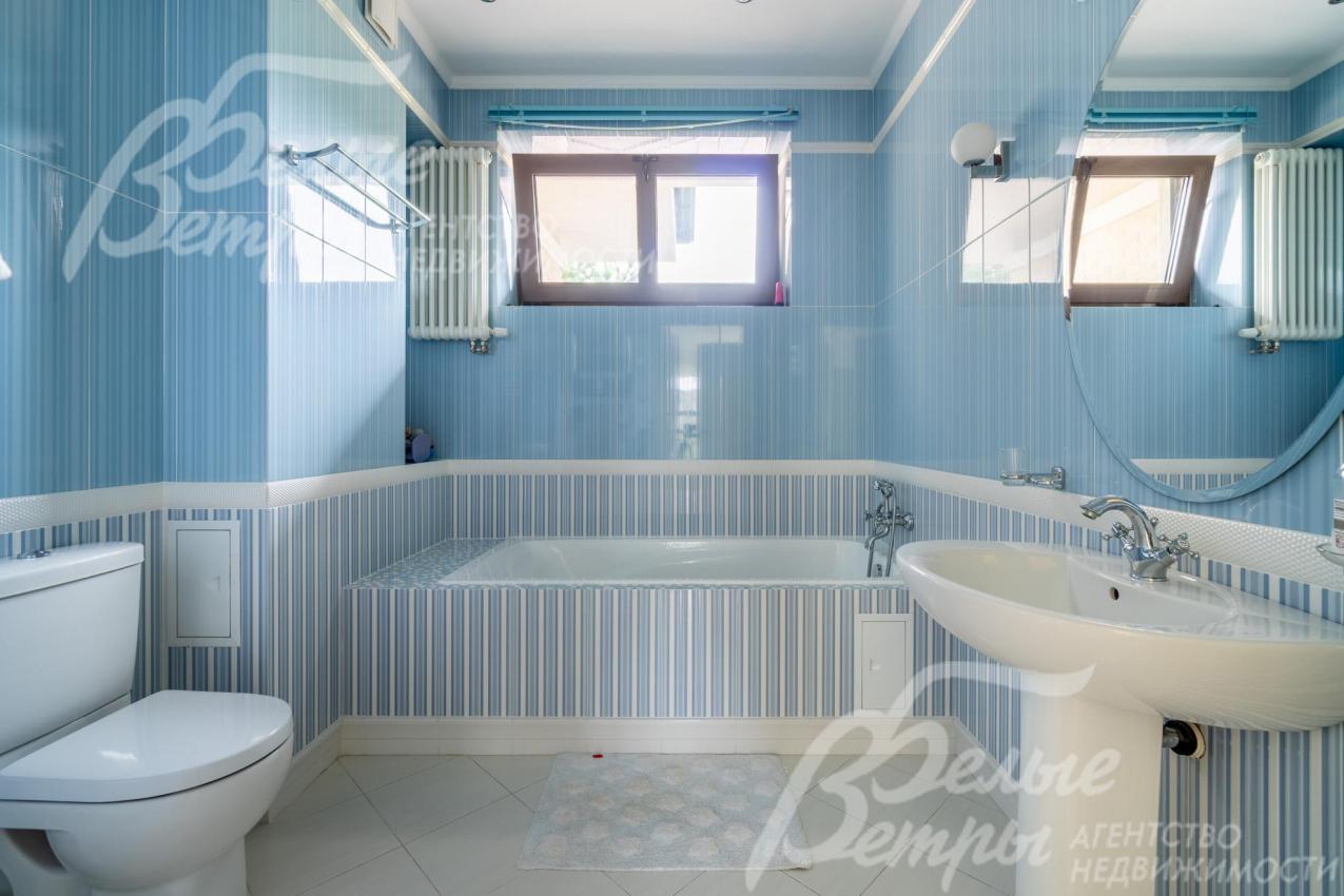 Санузел на втором этаже, оформленный в бело-голубых оттенках, с ванной у окна