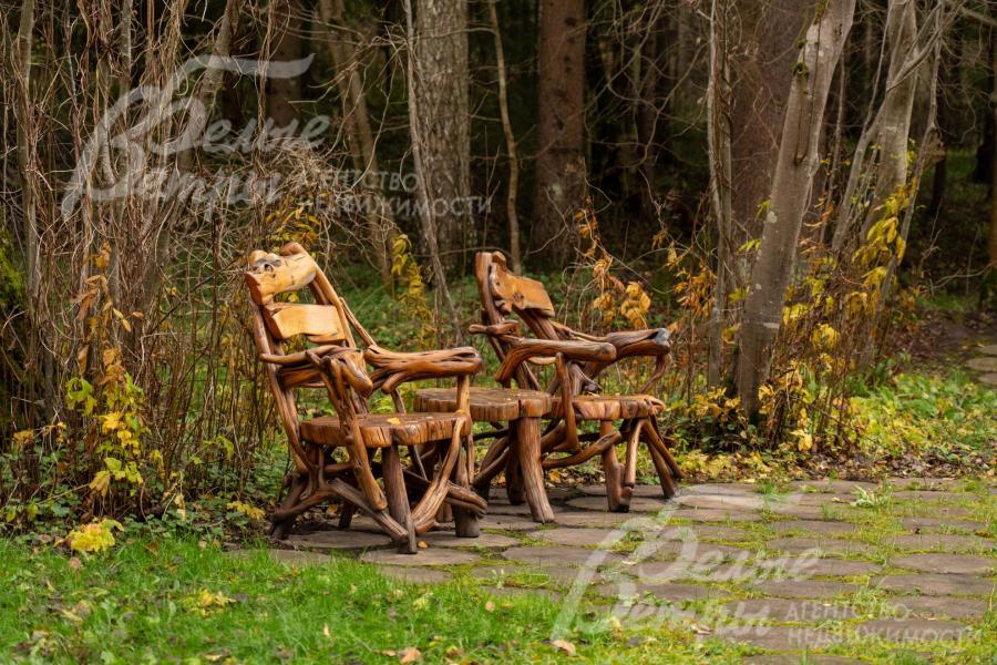 В тени раскидистых деревьев расположились уютные деревянные кресла со столиком