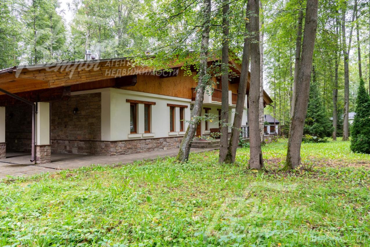 Цоколь дома отделан диким камнем, 1-й этаж - декоративной штукатуркой, 2-й этаж - лиственницей