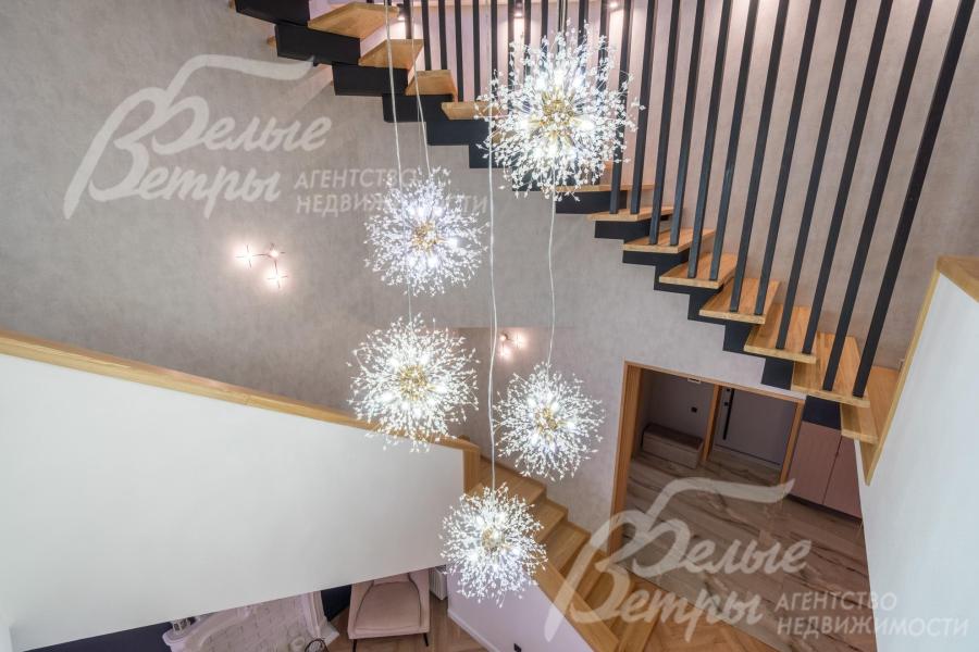 По центру над лестницей располагается эффектная подвесная люстра в стиле «одуванчик»