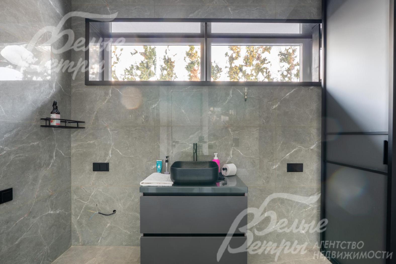 Чёрная прямоугольная раковина у окна гармонично сочетается с общим цветовым решением и подчёркивает сдержанную элегантность интерьера