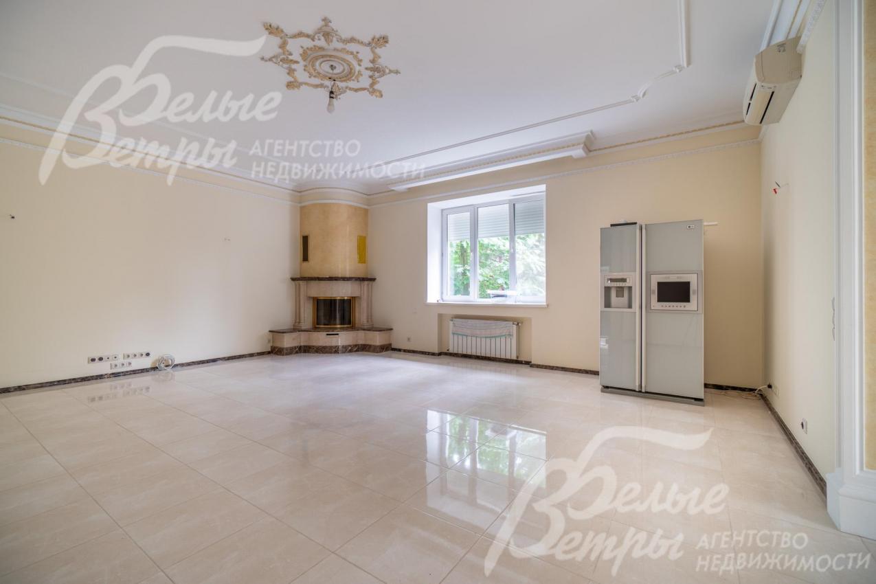 Просторную гостиную украшает угловой камин и декоративная роспись на потолке