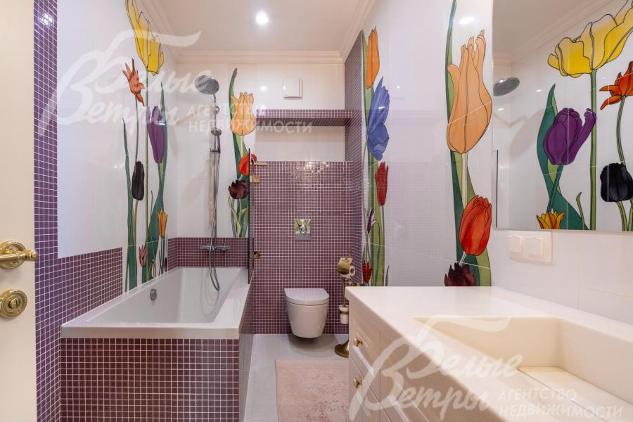 Санузел на втором с ванной с оригинальным дизайнерским оформлением: стены украшены крупными красочными рисунками тюльпанов в насыщенных оттенках