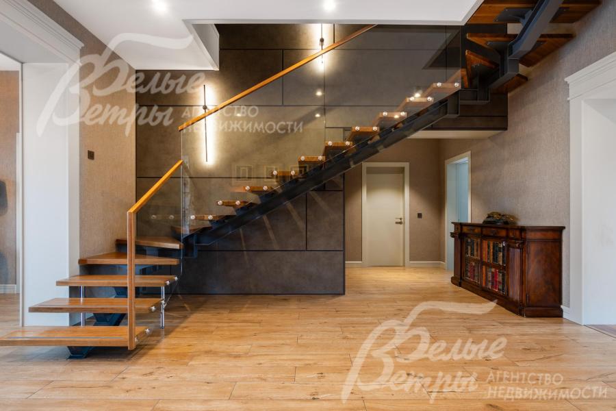 Эффектная  лестница с «парящими» деревянными ступенями с освещением и стеклянными перилами сочетает современный минимализм с тёплыми натуральными оттенками