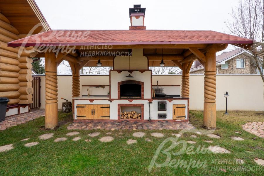 На участке - уличная кухня с крытым блоком в стилистике русской печи, интегрированной в деревянную беседку