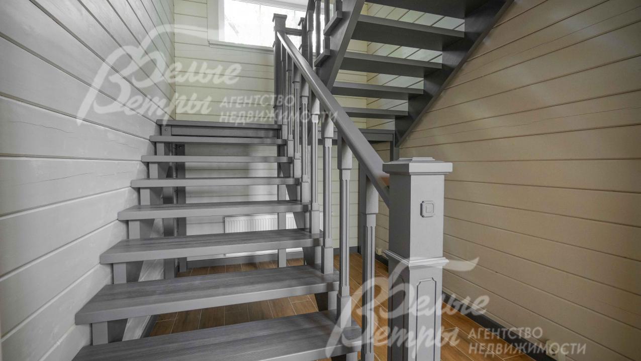 Широкая и удобная лестница из массива дуба, цвета графит. Из того же материала и той же стилистики - двери, плинтуса и кухня