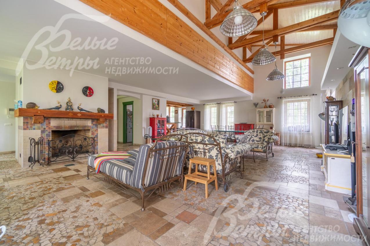 Просторная двусветная гостиная с камином, отделанным травертином