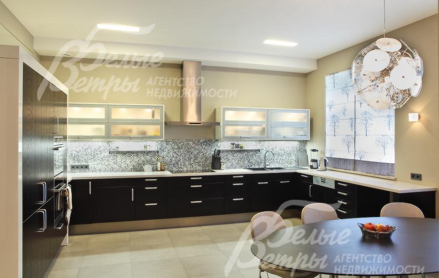 В кухне-столовой черный кухонный гарнитур с большой рабочей зоной.  