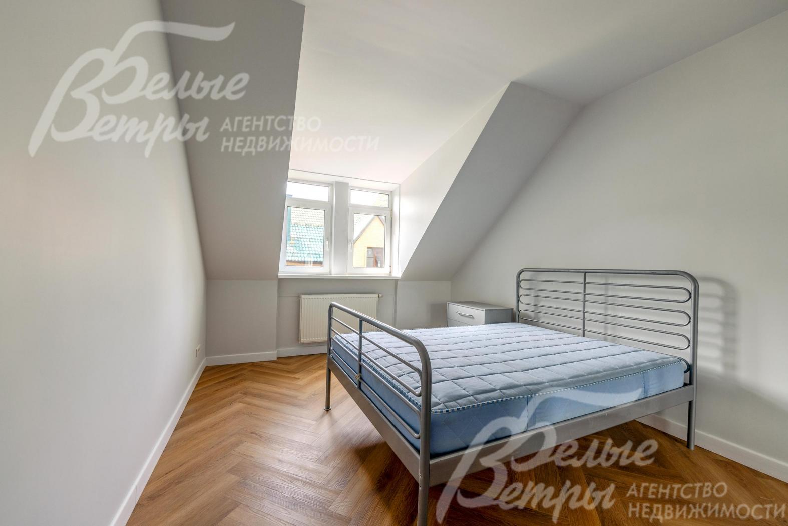 Одна из спален второго этажа со скошенными потолками, которые создают уютную атмосферу