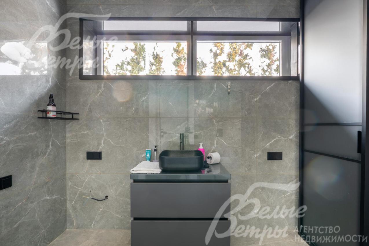 Чёрная прямоугольная раковина у окна гармонично сочетается с общим цветовым решением и подчёркивает сдержанную элегантность интерьера