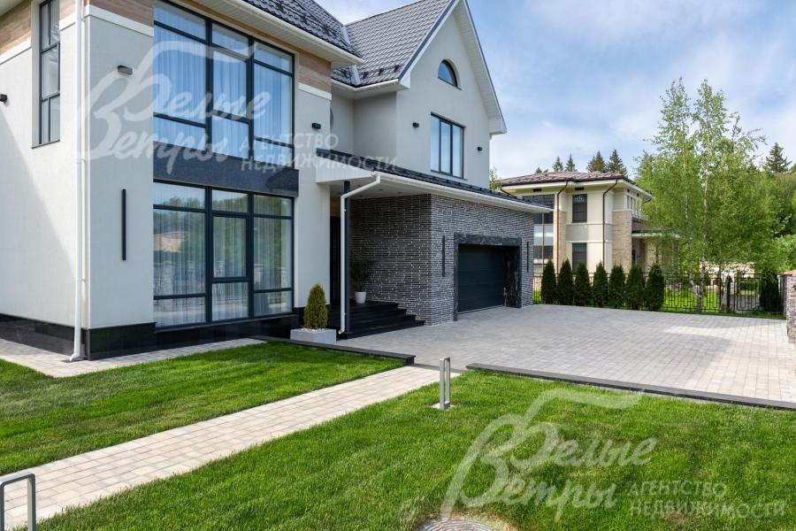 Дорожки участка вымощены плиткой, уложен профессиональный газон, выполнено ночное освещение