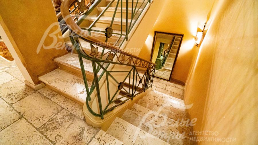 Лестничный марш облицован юрским камнем и обрамлен перилами с художественной ковкой