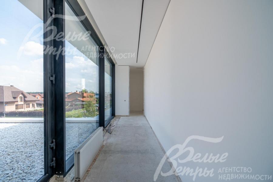 Коридор с панорамным остеклением: из окон открывается вид на участок и коттеджный посёлок