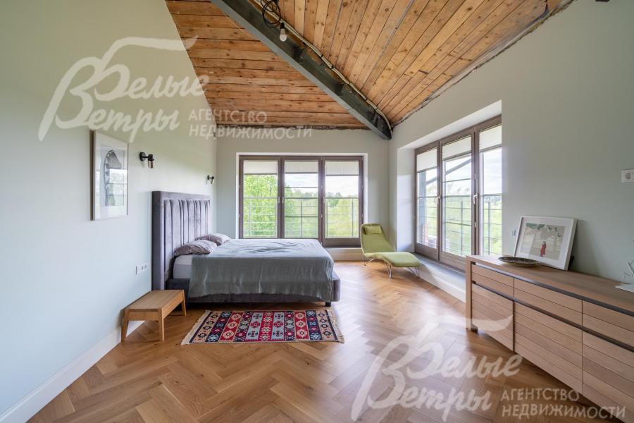 Первая мастер-спальня на втором этаже с большими окнами в пол, потолками из гипсокартона, отделанными деревом