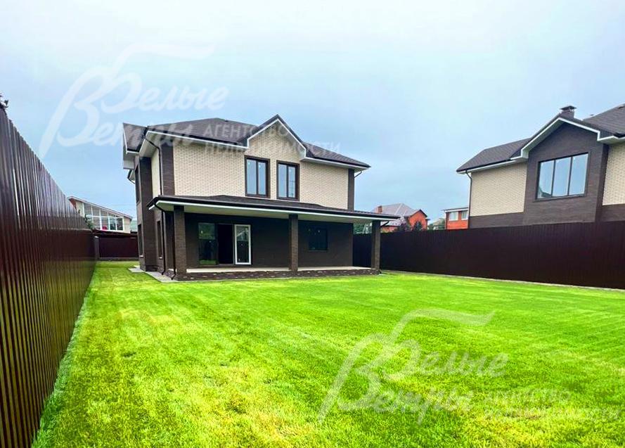 Дом стоит на ровном зелёном участке с газоном