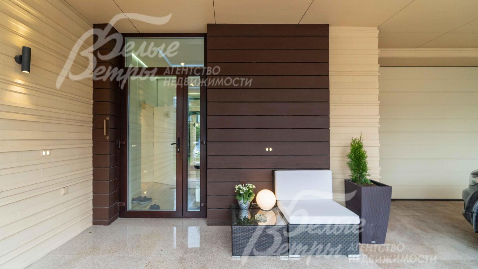 Главный вход в дом со стеклянной дверью, под большим нввесом