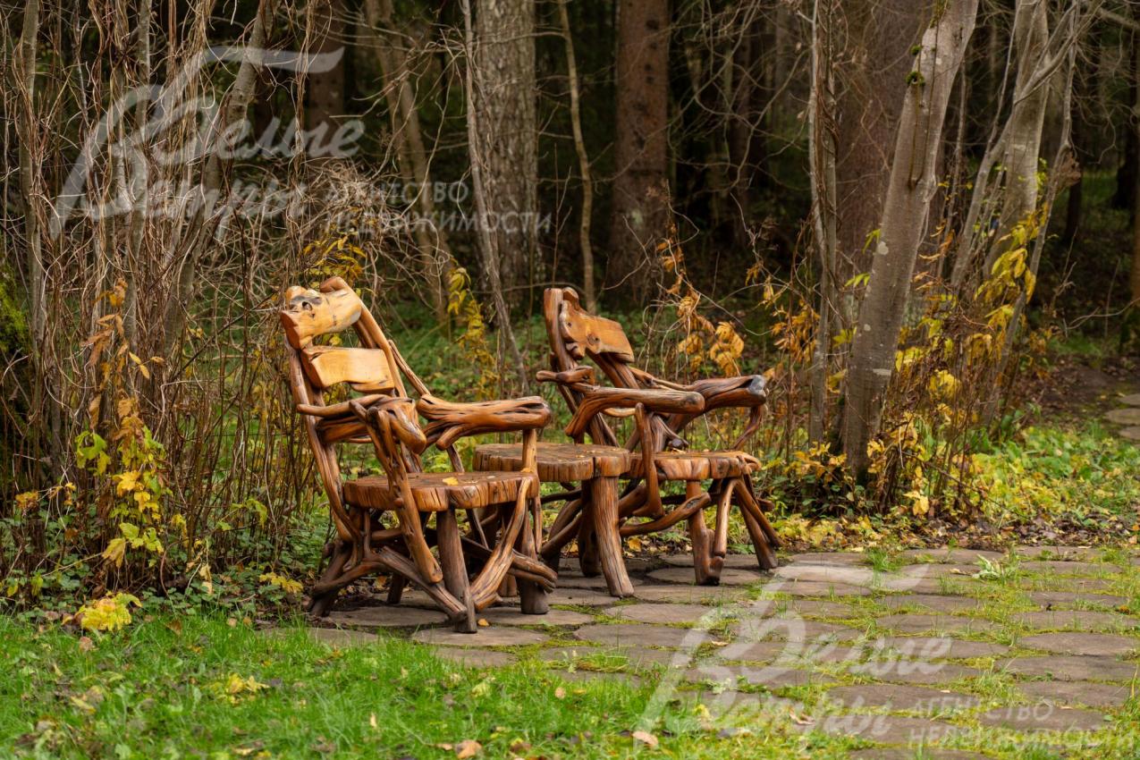 В тени раскидистых деревьев расположились уютные деревянные кресла со столиком