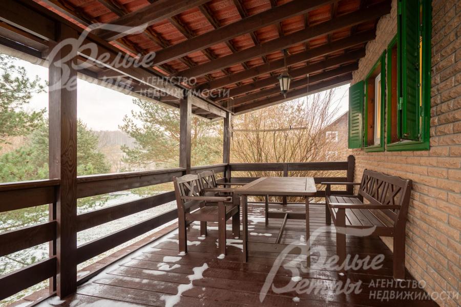 Крытая терраса дома с комплектом садовой мебели из массива дерева