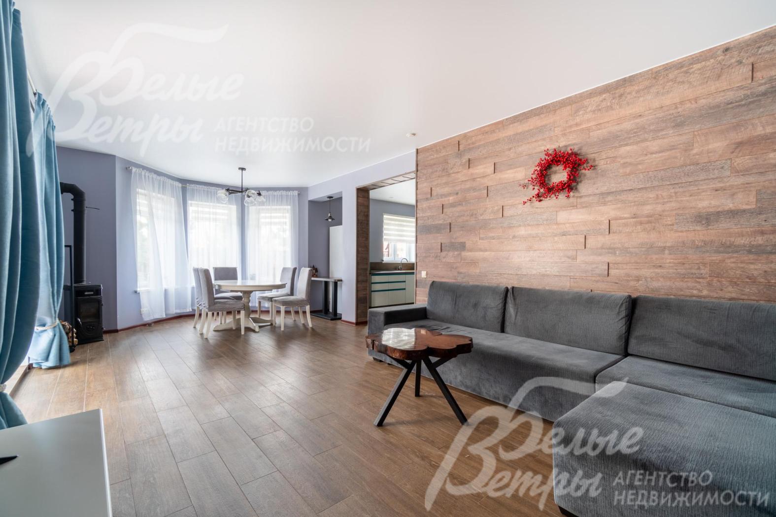 В доме выполнена стильная уютная отделка: в зоне гостиной - акцентная стена за диваном, оформленная панелями под дерево, которые гармонируют с оттенком напольного покрытия