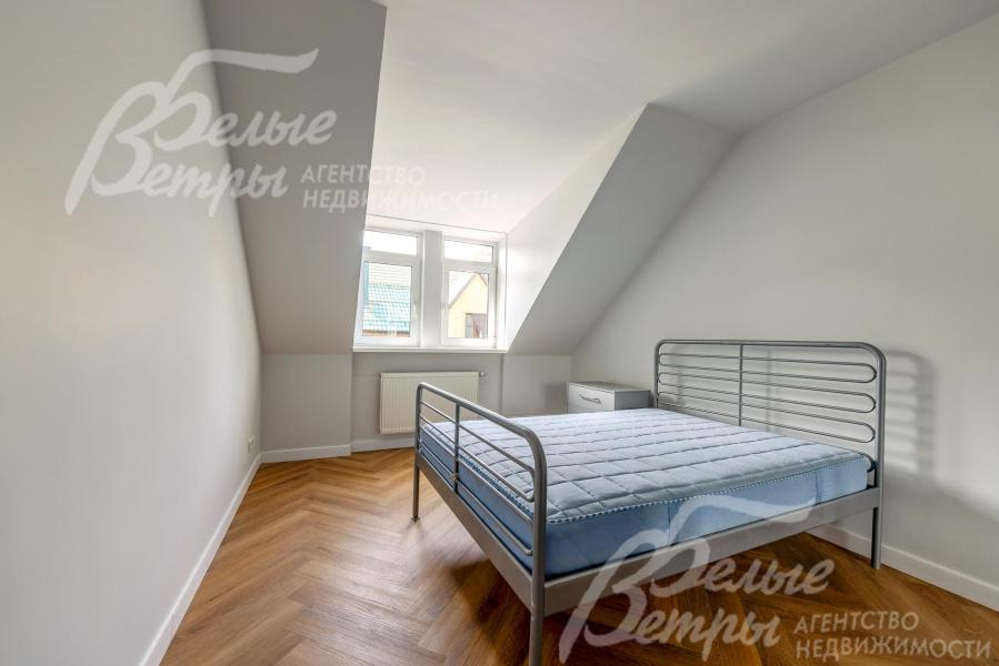 Одна из спален второго этажа со скошенными потолками, которые создают уютную атмосферу