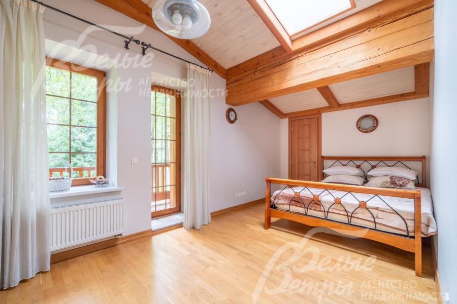 Уютная спальня на втором этаже с выходом на балкон, тёплую атмосферу в ней создаёт натуральная деревянная отделка