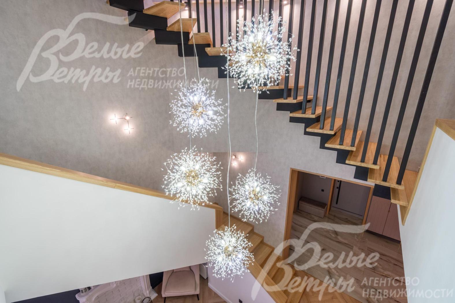 По центру над лестницей располагается эффектная подвесная люстра в стиле «одуванчик»
